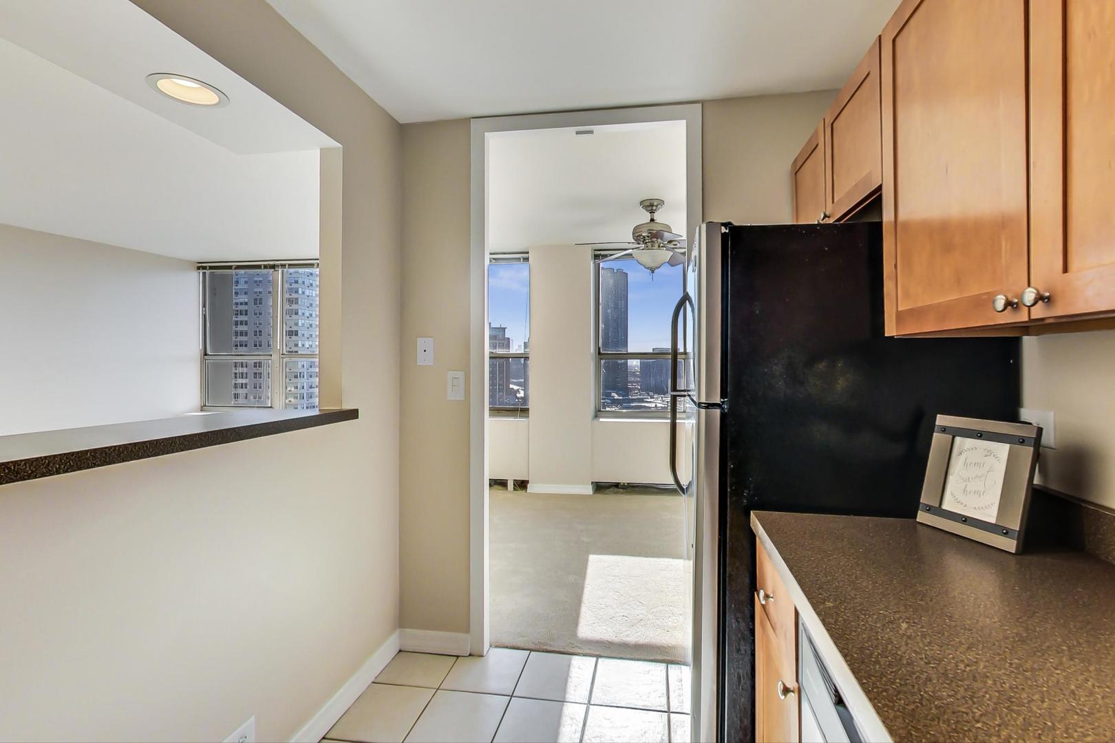 655 West Irving Park Road, Unit 1403 Chicago, IL 60613 - Photo 17 of 36 a kitchen with stainless steel appliances granite countertop a refrigerator a stove and a sink with wooden floor