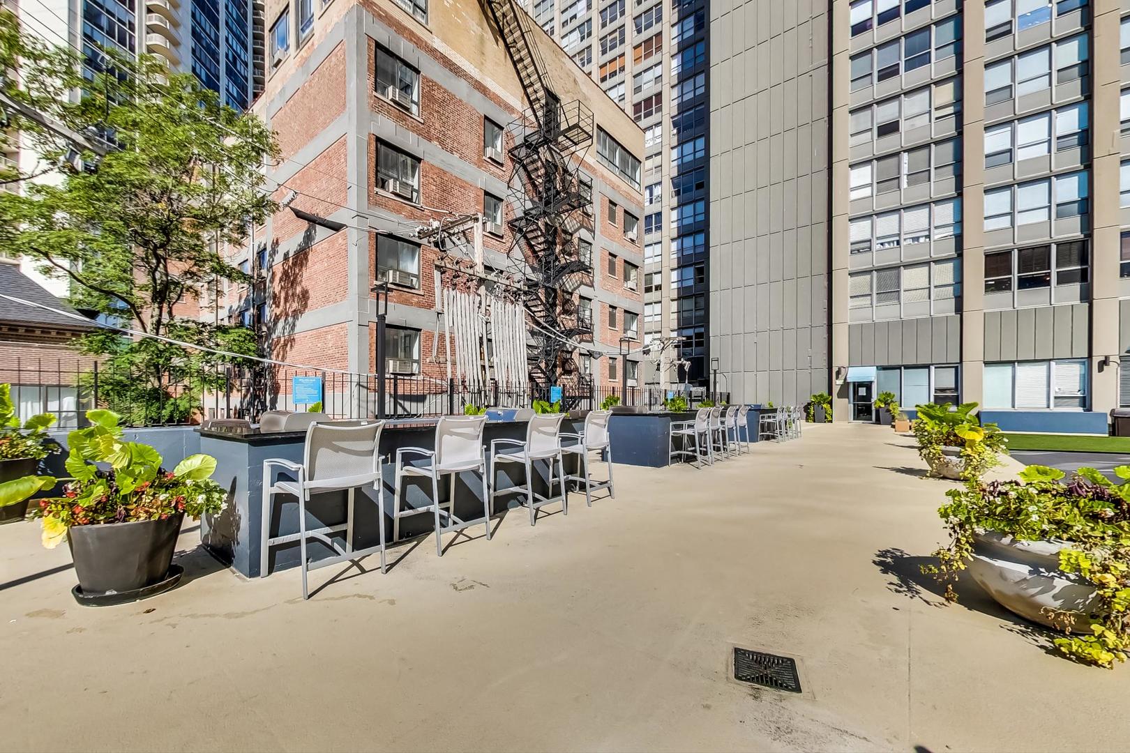 655 West Irving Park Road, Unit 1403 Chicago, IL 60613 - Photo 30 of 36 a view of a patio with dining table and chairs and potted plants