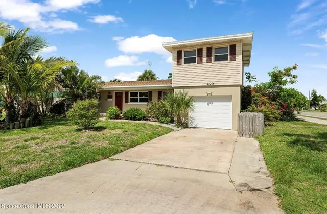 a front view of a house with a yard and potted plants