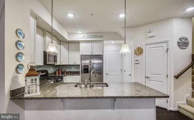 a kitchen with stainless steel appliances granite countertop a sink refrigerator and cabinets