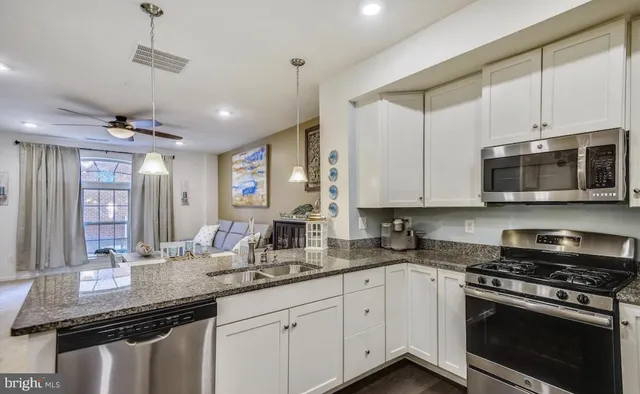 a kitchen with stainless steel appliances granite countertop a sink a stove and a microwave