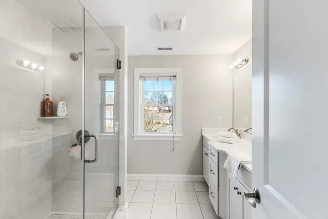 a bathroom with a granite countertop shower a sink and a mirror