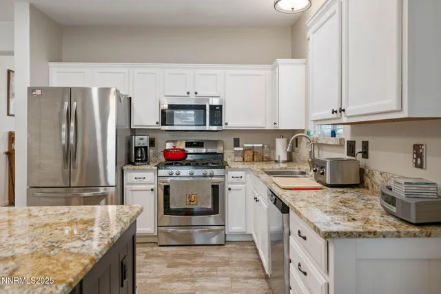 a kitchen with granite countertop white cabinets sink and stainless steel appliances