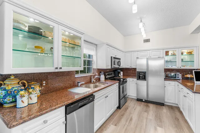 a kitchen with stainless steel appliances granite countertop a sink and a refrigerator