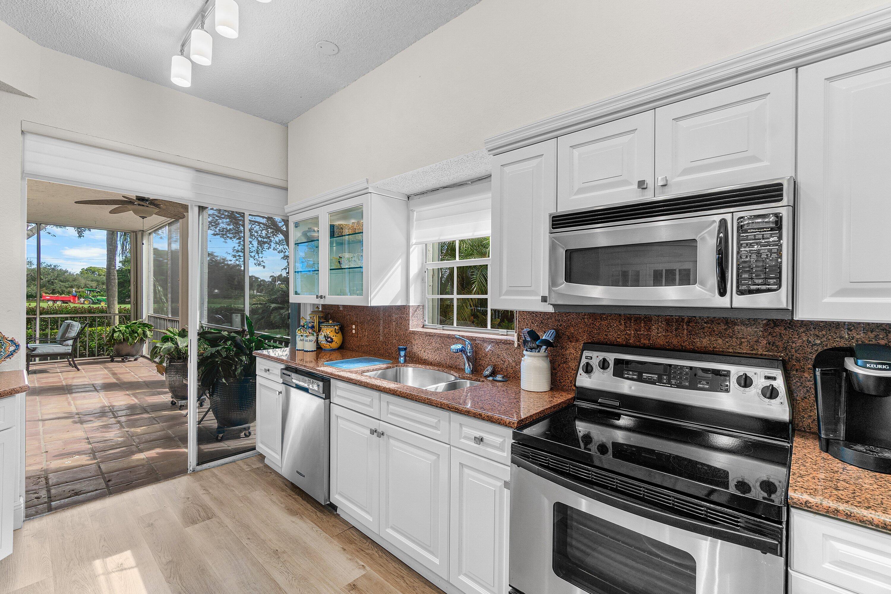 5100 Lake Catalina Drive, Unit C Boca Raton, FL 33496 - Photo 13 of 42 a kitchen with stainless steel appliances a stove a sink and a microwave