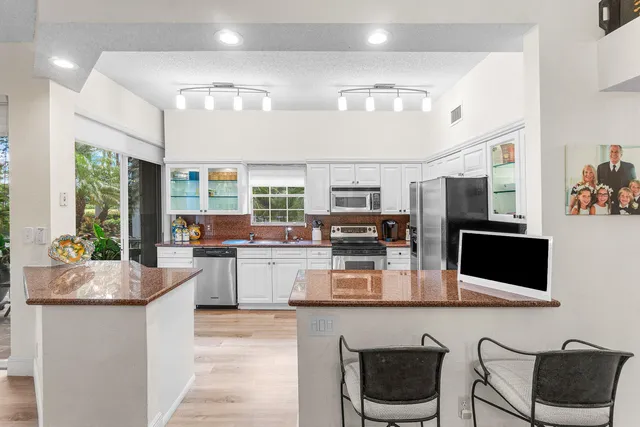 a kitchen with stainless steel appliances kitchen island granite countertop a refrigerator and microwave