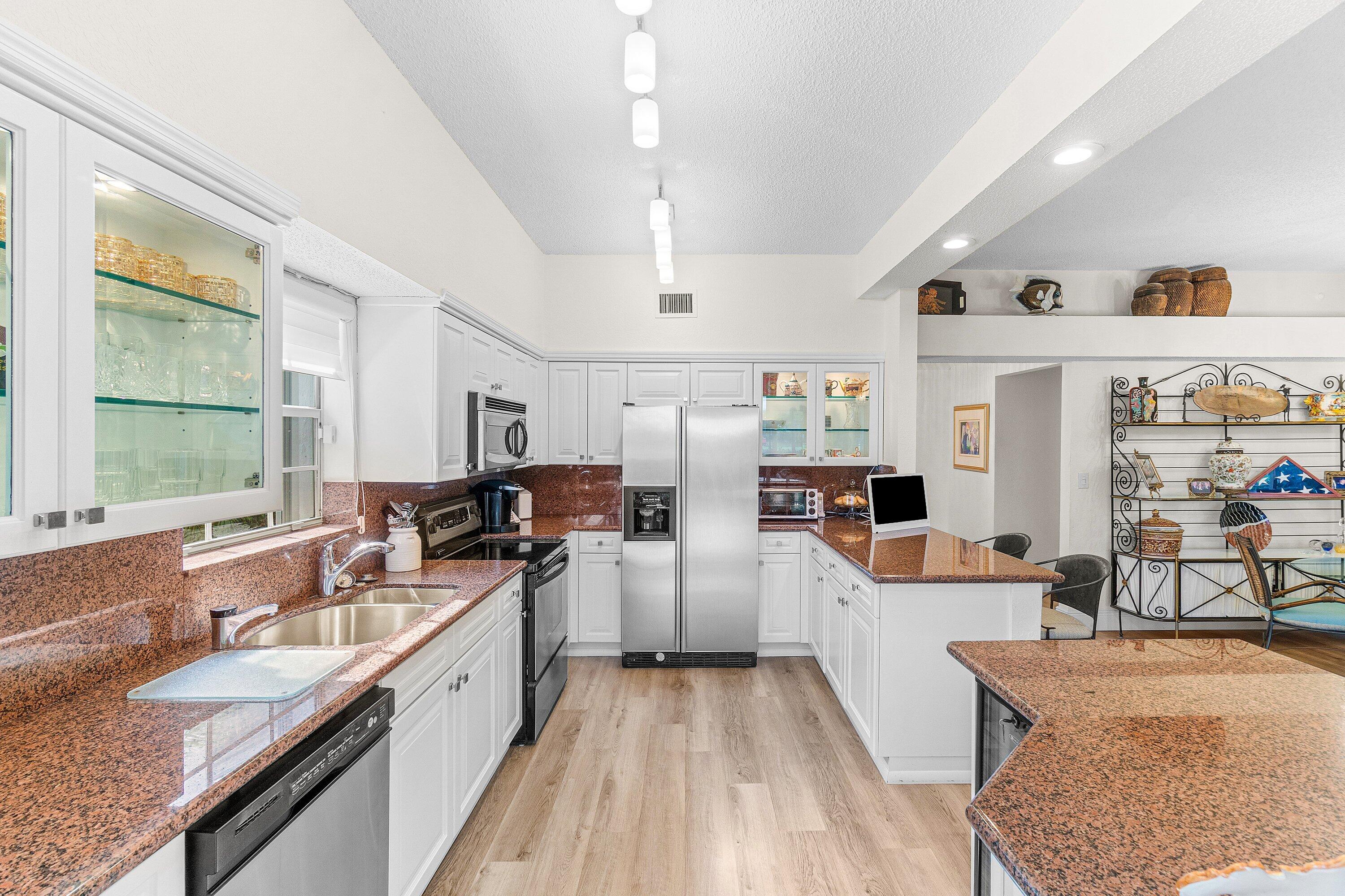 5100 Lake Catalina Drive, Unit C Boca Raton, FL 33496 - Photo 10 of 42 a large kitchen with stainless steel appliances kitchen island granite countertop a lot of counter space and a sink