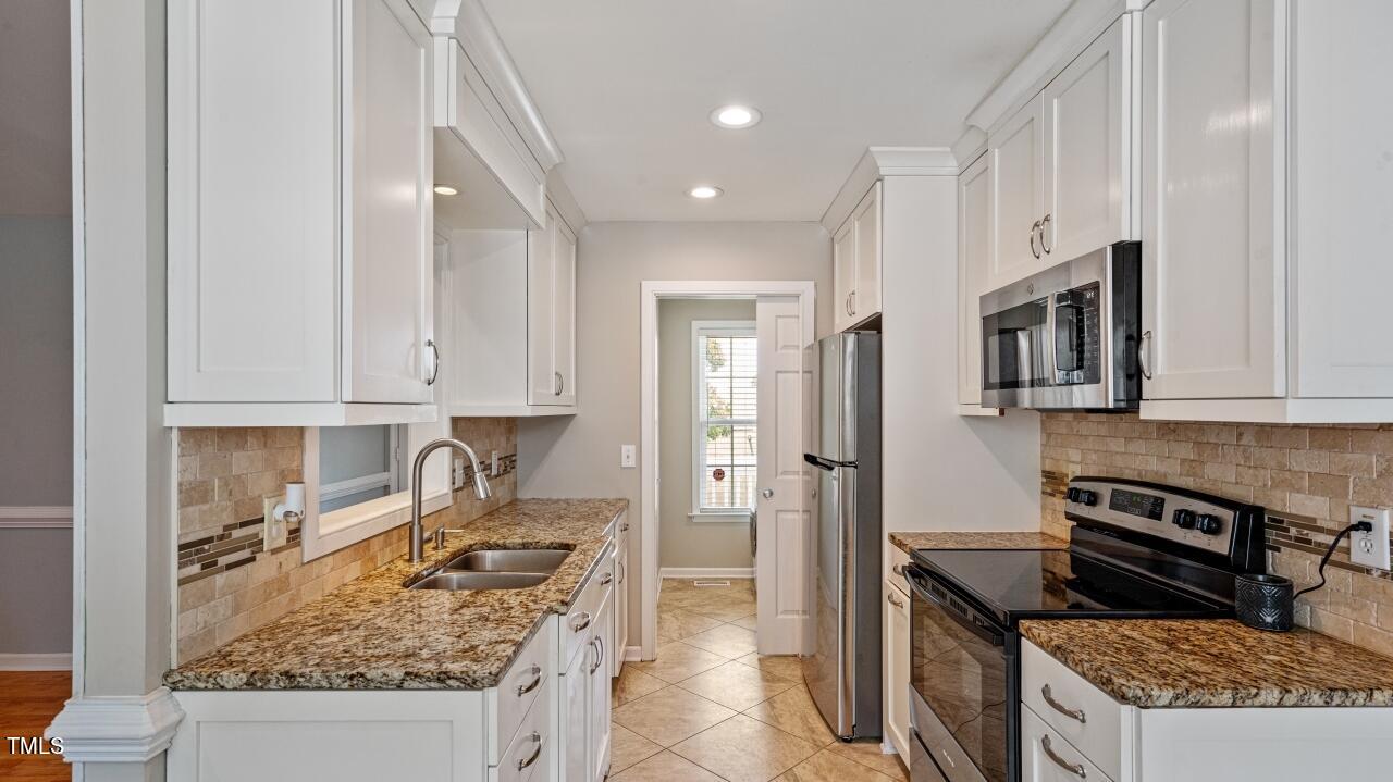 1065 Smith Road Smithfield, NC 27577 - Photo 12 of 36 a kitchen with stainless steel appliances granite countertop a stove top oven a sink a refrigerator and white cabinets