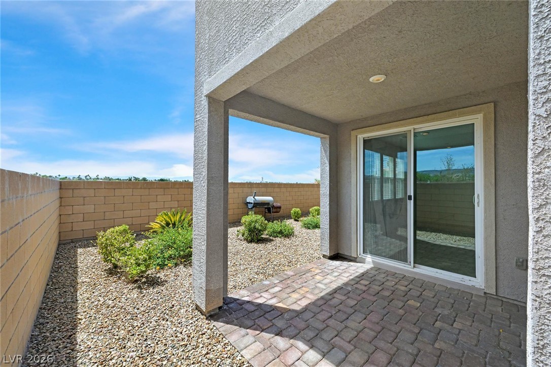 155 Fulgora Street Henderson, NV 89074 - Photo 21 of 30 A private, covered patio with pavers extends to a low-maintenance gravel yard, perfect for outdoor enjoyment.