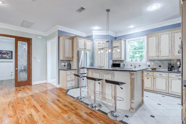 a kitchen with stainless steel appliances granite countertop a stove a sink dishwasher a refrigerator and white cabinets with wooden floor