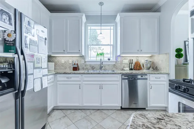 a kitchen with stainless steel appliances granite countertop a refrigerator sink and white cabinets