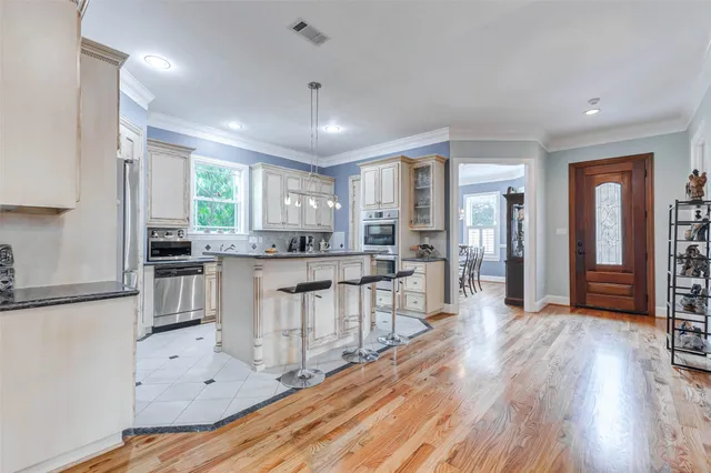 a kitchen with stainless steel appliances granite countertop a refrigerator a sink dishwasher a stove and white countertops with wooden floor