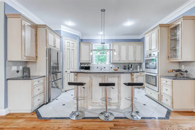 a kitchen with stainless steel appliances kitchen island granite countertop a refrigerator and cabinets