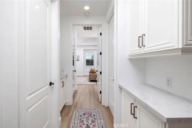 a hallway with white cabinets and wooden floor