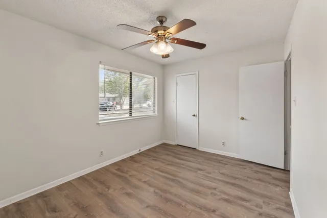 a view of an empty room with window and chandelier fan