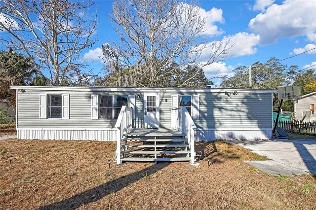 a view of house with backyard and trees in the background
