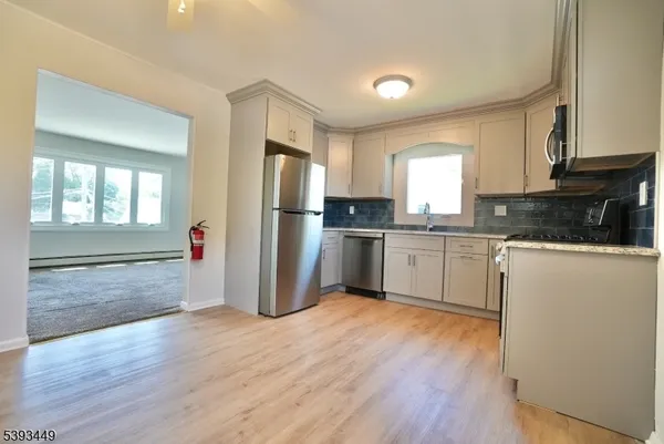 a kitchen with granite countertop a refrigerator and wooden floors