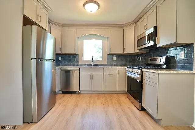 a kitchen with stainless steel appliances granite countertop a refrigerator a sink dishwasher a stove with wooden floor and cabinets