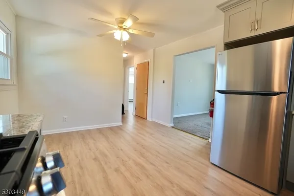 a view of a kitchen with a refrigerator a ceiling fan and wooden floor