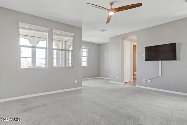 an empty room with windows and fan