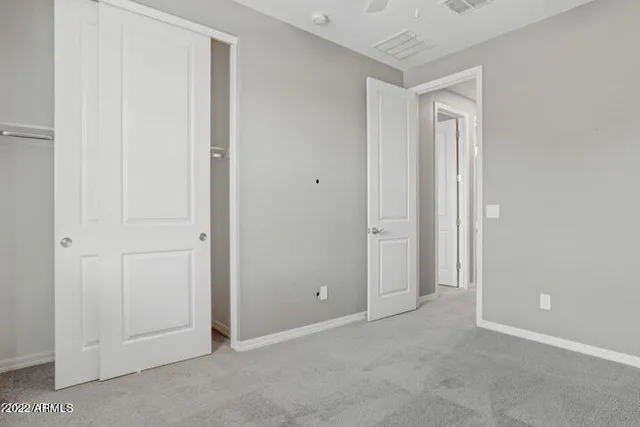 an empty room with closet and a chandelier fan