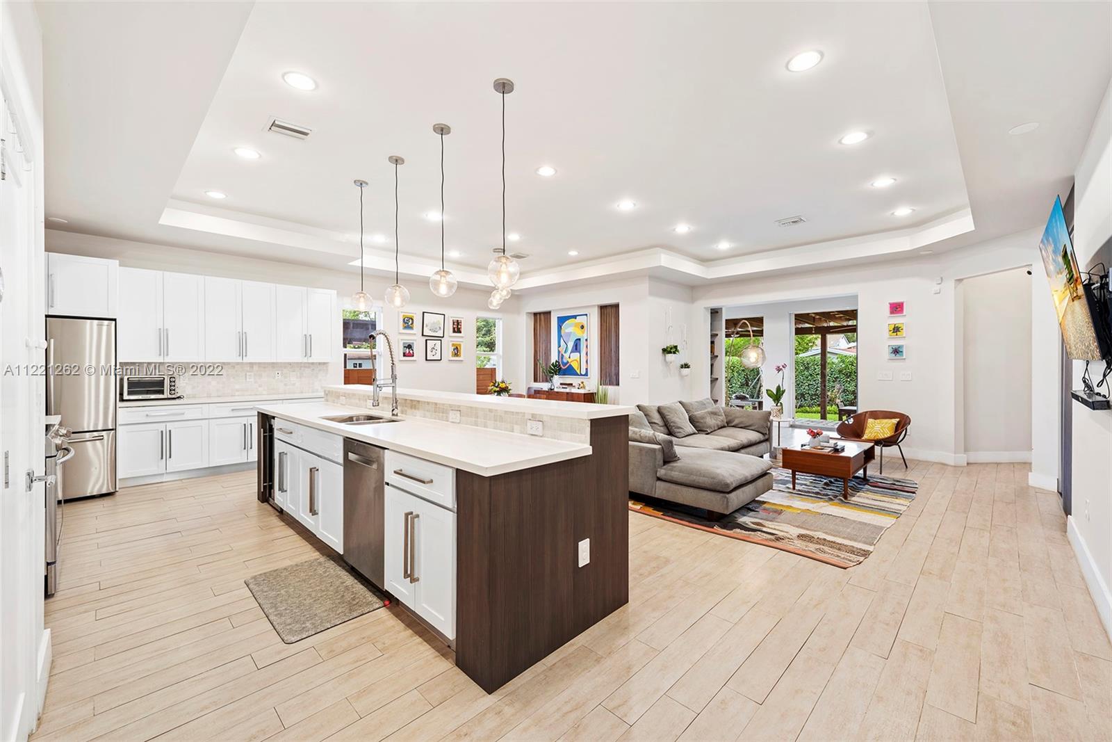 2321 Southwest 19th Street Miami, FL 33145 - Photo 4 of 29 a large kitchen with stainless steel appliances kitchen island granite countertop a large kitchen island a stove a sink a dining table and chairs with wooden floor