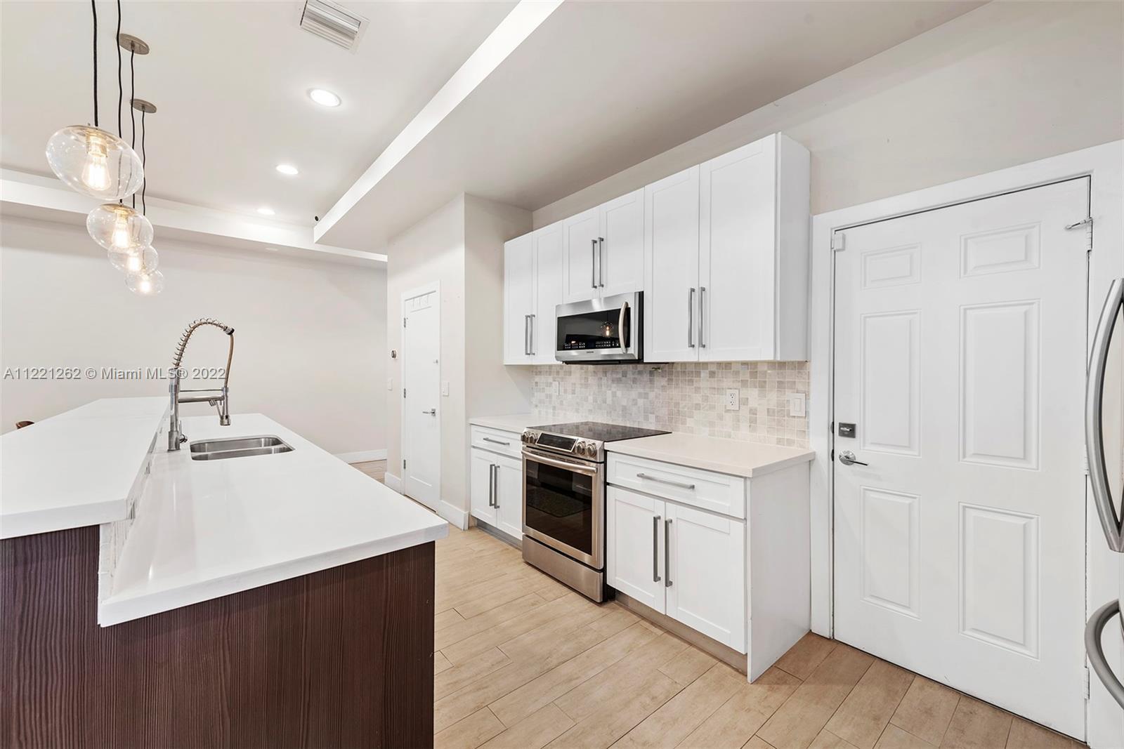 2321 Southwest 19th Street Miami, FL 33145 - Photo 7 of 29 a kitchen with stainless steel appliances a sink dishwasher a refrigerator and a stove top oven with wooden floor