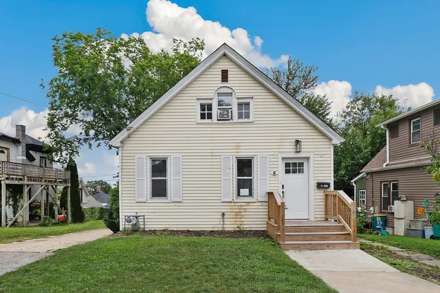 a view of a white house next to a yard with big trees
