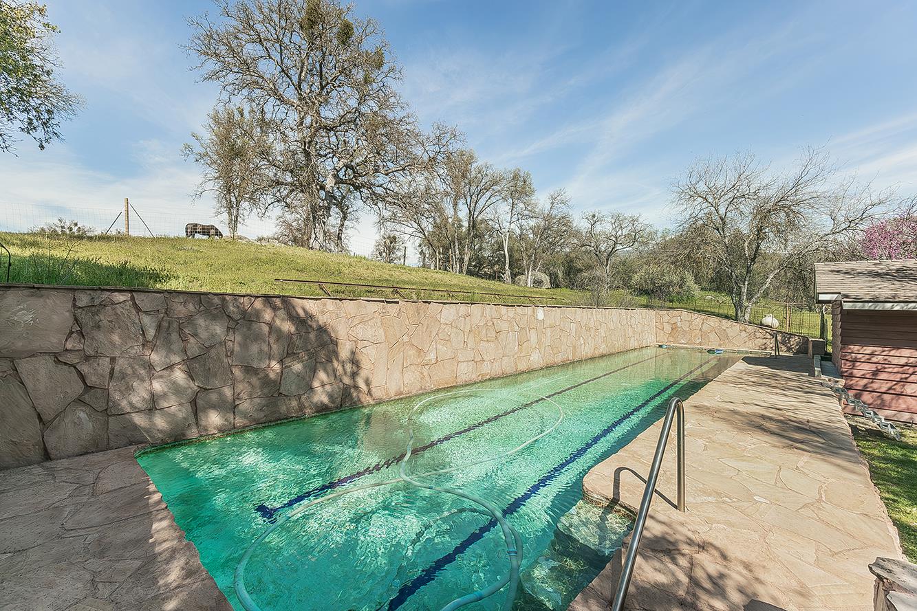 31638 Lodge Road Auberry, CA 93602 - Photo 47 of 90 a view of a backyard with lawn chairs under an umbrella