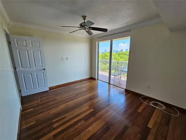 a view of empty room with wooden floor and fan