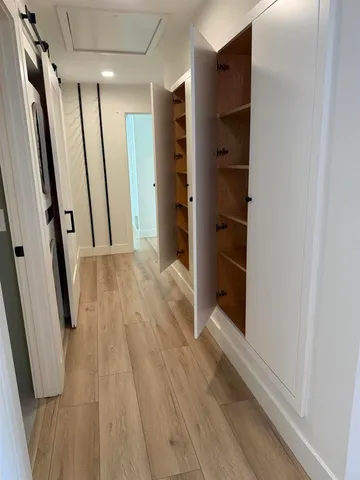 a view of hallway with walk in closet and wooden floor