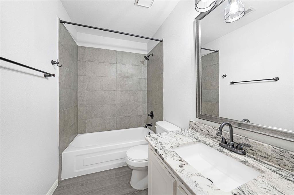 2200 East Trinity Mills Road, Unit 510 Carrollton, TX 75006 - Photo 12 of 17 a bathroom with a granite countertop bathtub shower sink vanity mirror and toilet