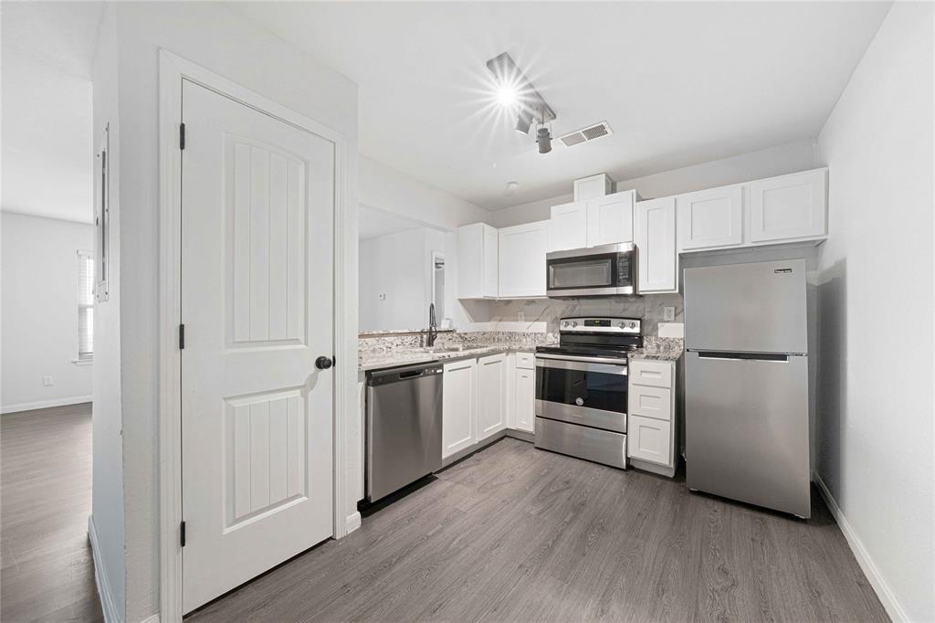 2200 East Trinity Mills Road, Unit 510 Carrollton, TX 75006 - Photo 2 of 17 a kitchen with stainless steel appliances a refrigerator a stove a microwave and white cabinets