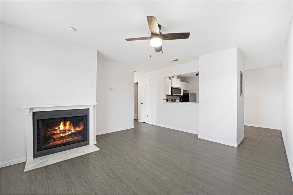 2200 East Trinity Mills Road, Unit 510 Carrollton, TX 75006 - Photo 5 of 17 a view of an empty room with wooden floor fireplace and a window