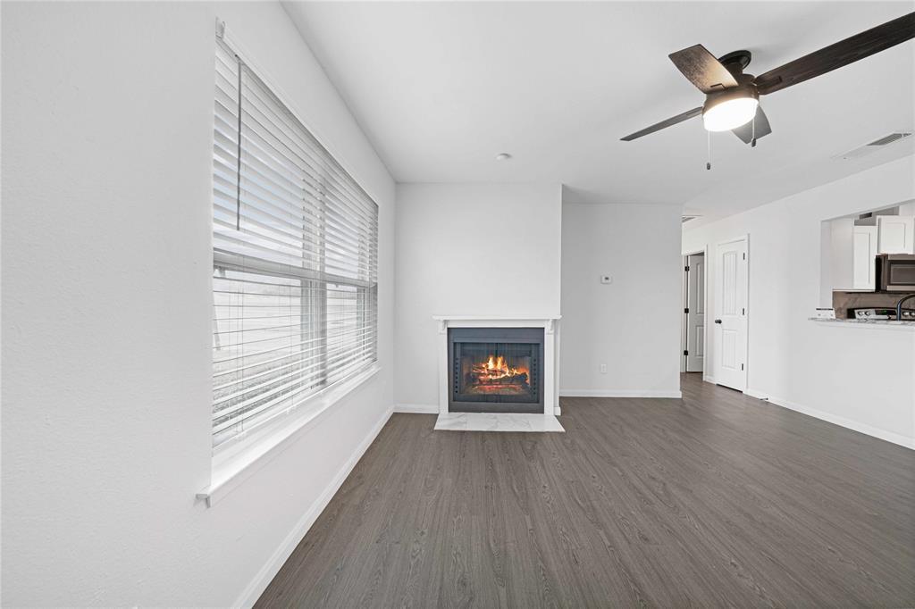2200 East Trinity Mills Road, Unit 510 Carrollton, TX 75006 - Photo 6 of 17 an empty room with wooden floor fireplace and windows