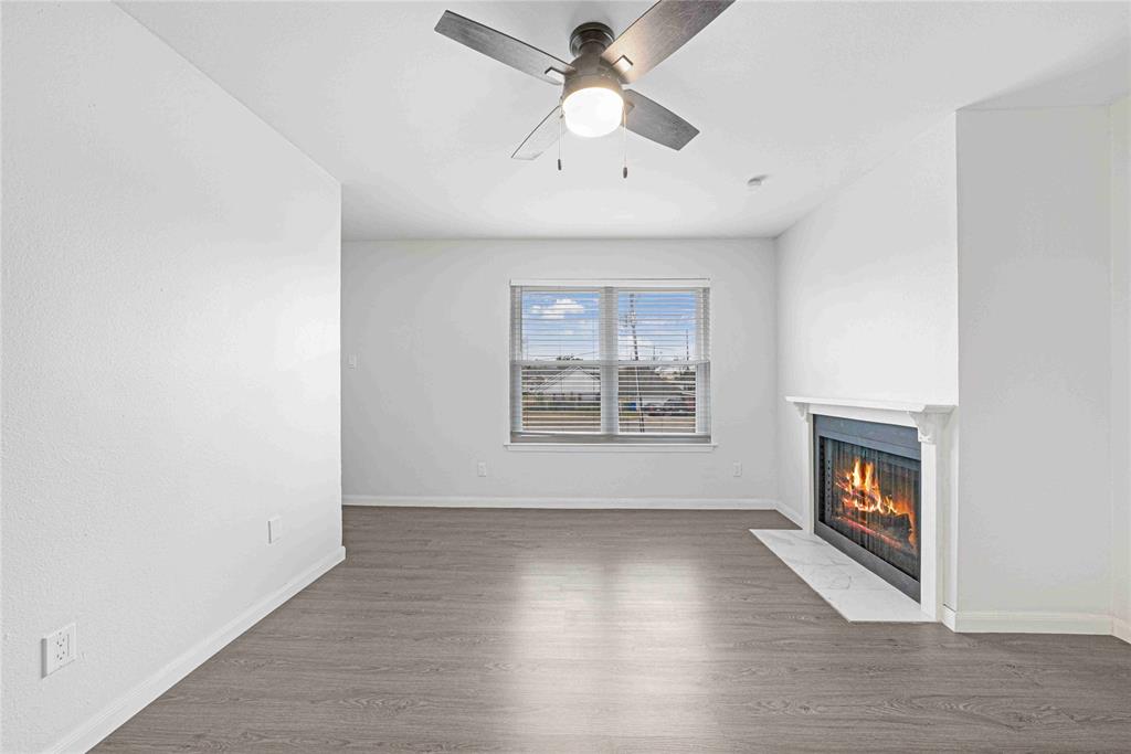 2200 East Trinity Mills Road, Unit 510 Carrollton, TX 75006 - Photo 7 of 17 an empty room with wooden floor chandelier fan and windows