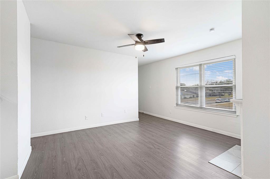 2200 East Trinity Mills Road, Unit 510 Carrollton, TX 75006 - Photo 8 of 17 an empty room with wooden floor chandelier fan and windows