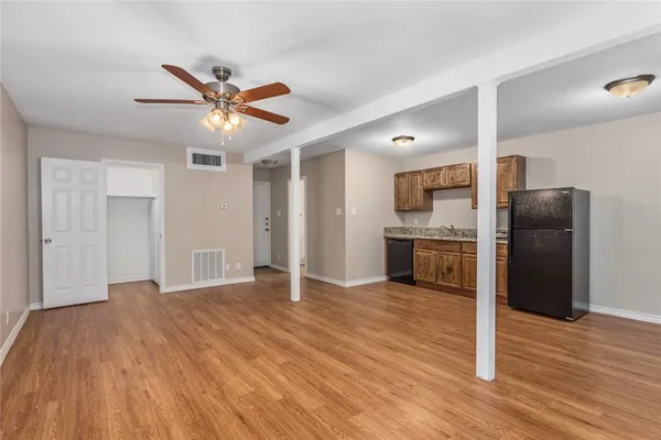 a view of a kitchen with wooden floor a ceiling fan and stainless steel appliances