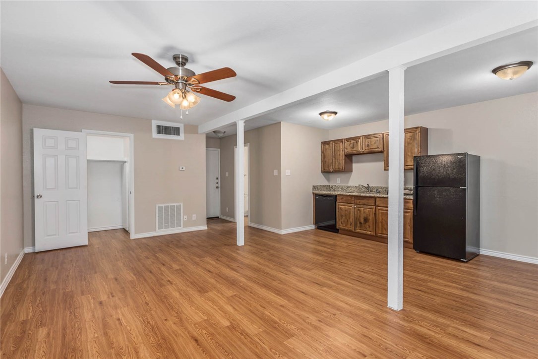 3914 Old College Road Bryan, TX 77801 - Photo 5 of 12 a view of a kitchen with wooden floor a ceiling fan and stainless steel appliances