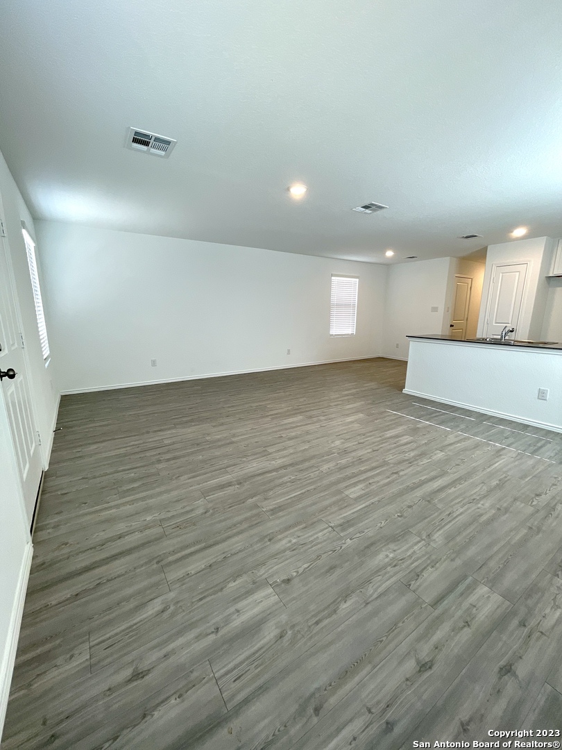 7274 Pasture Run San Antonio, TX 78252 - Photo 3 of 17 an empty room with wooden floor and windows