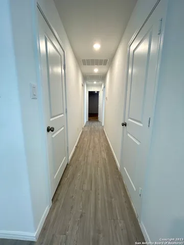 a view of a hallway with wooden floor and a bathroom