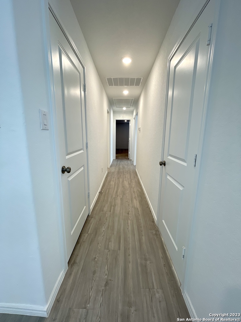 7274 Pasture Run San Antonio, TX 78252 - Photo 7 of 17 a view of a hallway with wooden floor and a bathroom