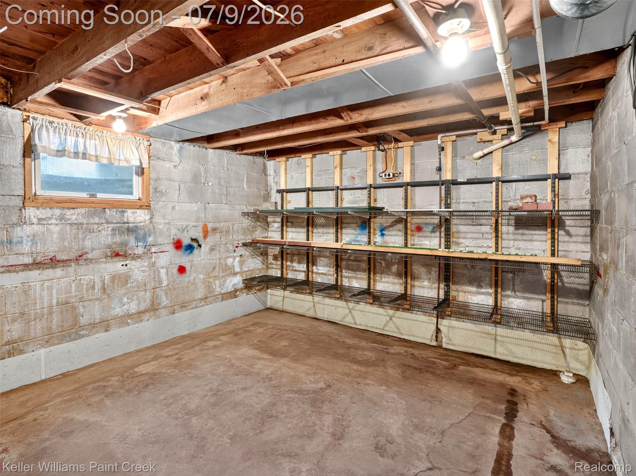 204 Russell Road Kawkawlin, MI 48631 - Photo 50 of 82 Unfinished basement space featuring exposed wood joists, concrete block walls, a concrete floor, and built-in shelving units