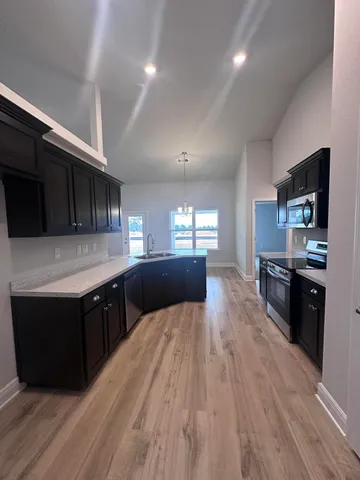 a large kitchen with stainless steel appliances wooden cabinets a stove a sink and a refrigerator