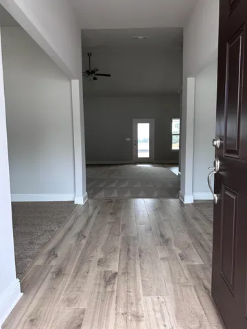a view of a hallway with wooden floor and a living room