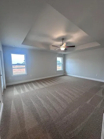 an empty room with windows and ceiling fan