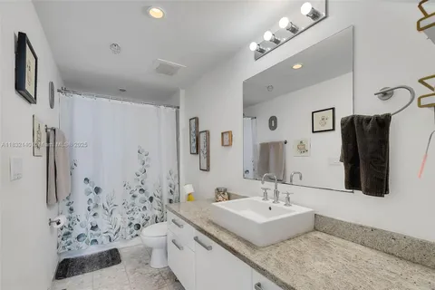 a bathroom with a granite countertop sink a toilet a mirror and shower