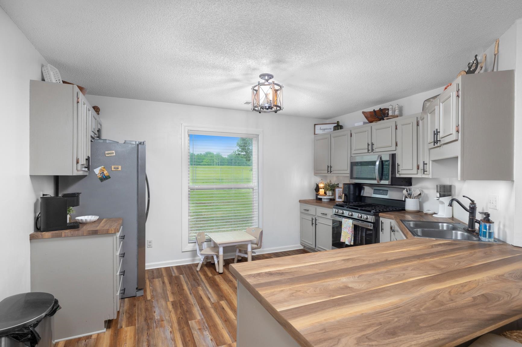 586 Beaver Road Munford, TN 38058 - Photo 7 of 21 Kitchen featuring wood-finish flooring, light gray cabinetry with black hardware, and wood-finish countertops