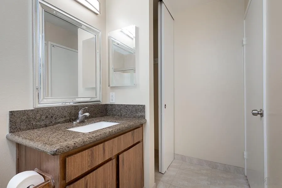 6046 Rancho Mission Road, Unit 384 San Diego, CA 92108 - Photo 13 of 18 a bathroom with a granite countertop sink and a mirror