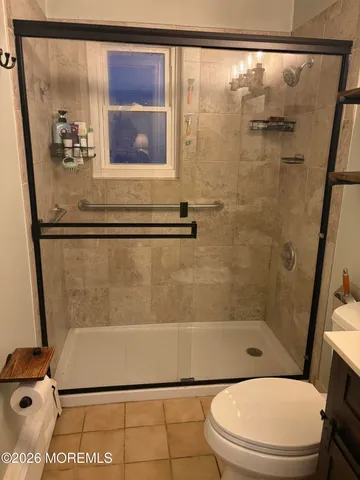 a bathroom with a sink a toilet a mirror and shower